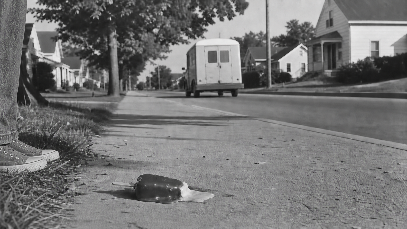 A dropped chocolate-covered ice cream bar melting on a neighborhood sidewalk as a boy stands on the grass and an ice cream truck drives away.