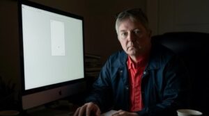 Allen Reding sitting at a desk in a dimly lit office, staring seriously at the camera, representing the universal feeling of being "stuck."